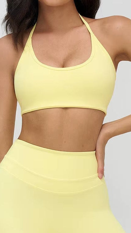 Person wearing a yellow sports bra and leggings set on a white background