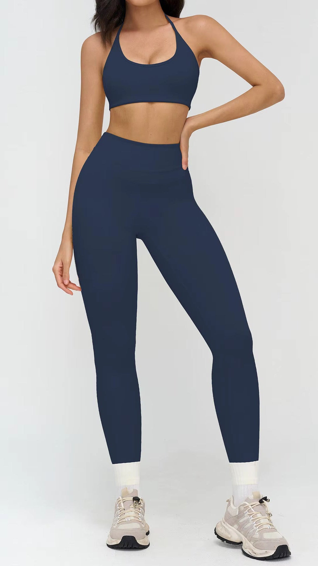 Person wearing a navy blue sports bra and leggings set on a white background