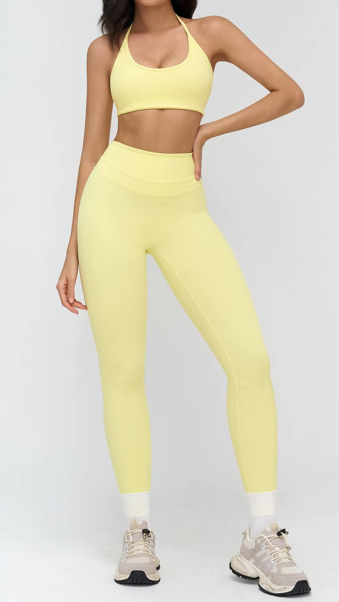 Person wearing a yellow sports bra and leggings set on a white background