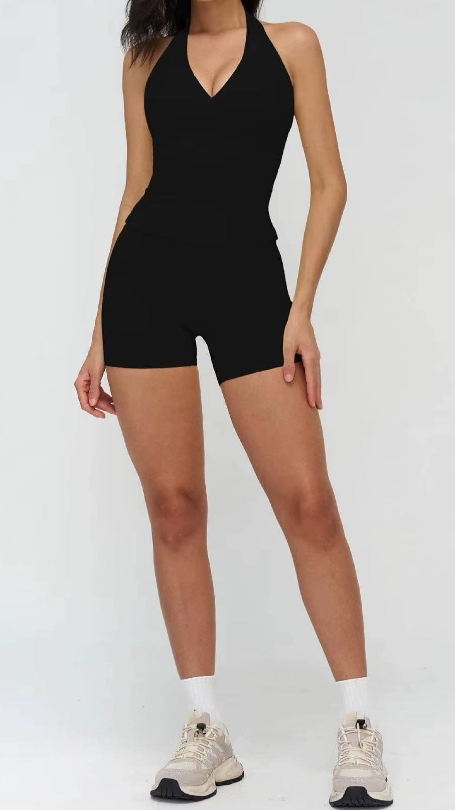 Person wearing a black halter neck romper on a white background